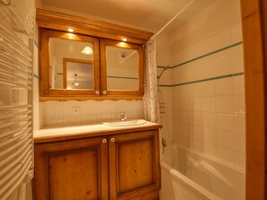 Une salle de bain avec un meuble-lavabo en bois, un miroir, un lavabo et une baignoire.