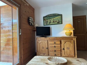 A wooden interior with a television, a lamp, and a wall-mounted sign. - Apartment for 7, ski-in/ski-out, balcony (Morillon 1100)