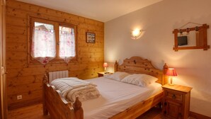 Ein Schlafzimmer aus Holz mit einem Bett, Nachttischlampen und einem Fenster mit Vorhängen.