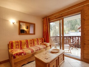 A wooden interior with a sofa, a wooden table, and a balcony with chairs. - Apartment for 7, ski-in/ski-out, balcony (Morillon 1100)
