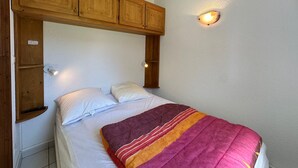 Ein Einzelbett mit Holz-Kopfteil, zwei Nachttischlampen und einer Wandleuchte.