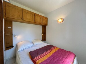 A single bed with a wooden headboard, two bedside lamps, and a wall-mounted light fixture. - Cozy apartment for 6 with mountain balcony (Morillon 1100)
