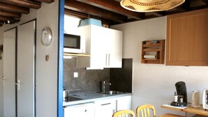 Una cocina compacta con armarios blancos, microondas, lavamanos y una mesa de comedor con sillas.
