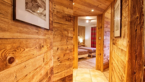 A wooden hallway leading to a bedroom with a bed and a nightstand. - Charming apartment in renovated farmhouse, sauna & terrace (Morillon Village)