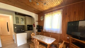A wooden interior with a dining table, chairs, a kitchen area, and a television. - Comfortable apartment for 4 in a picturesque village (Morillon Village)