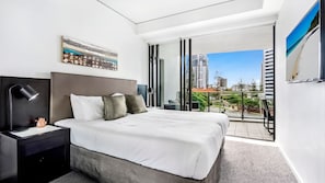 Relax in a spacious room with a large bed, city views, and a balcony with outdoor seating.