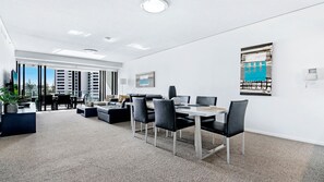 Un espace de bureau moderne dot é d’un coin repas, de grandes fenêtres et d’une vue sur le paysage urbain.
