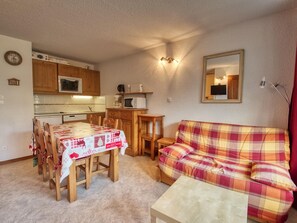 A cozy living room with a plaid sofa and a dining table set for four.