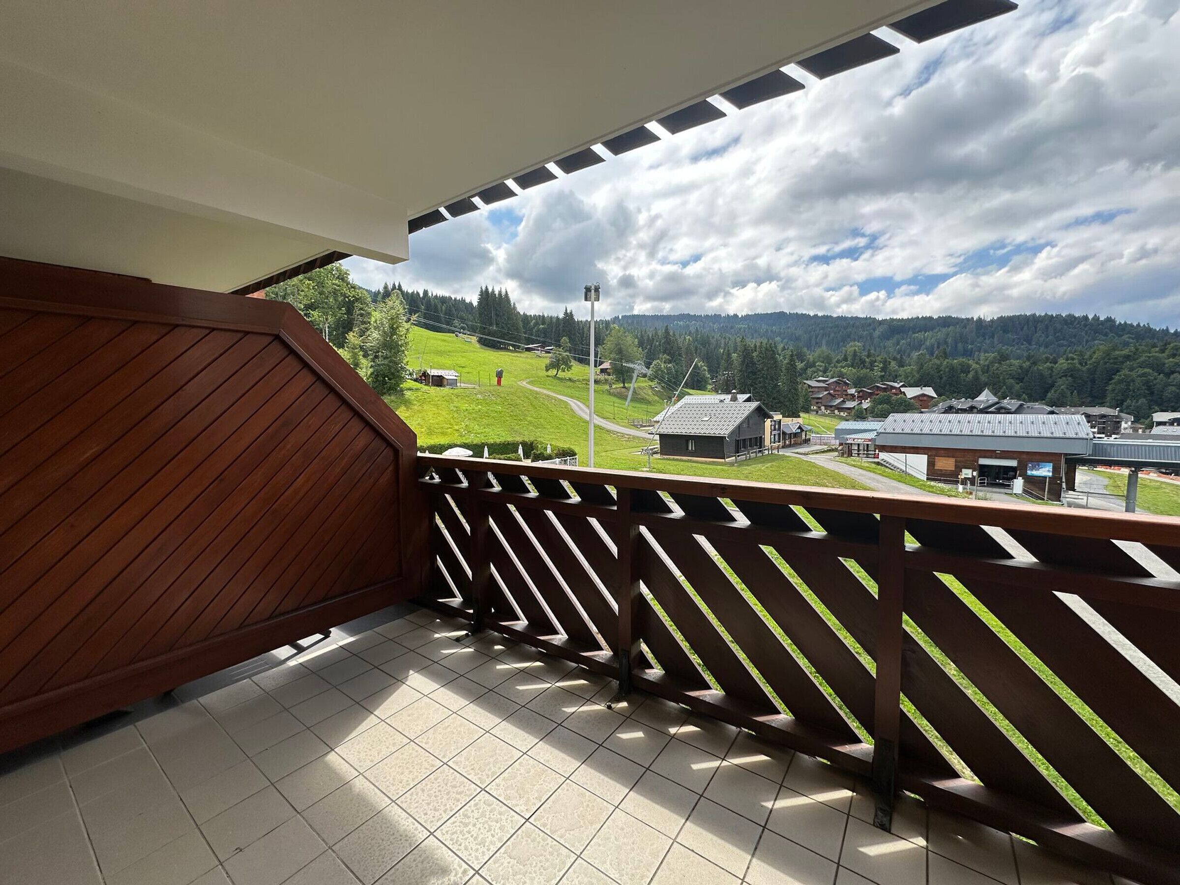 Ein Balkon mit Blick auf eine grüne Landschaft und Gebäude.
