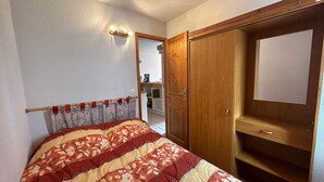 A bedroom with a bed, wooden wardrobe, and a mirror.