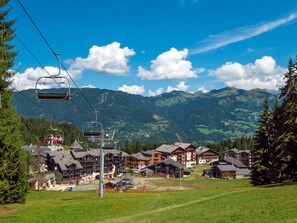 A mountain resort with ski lifts, wooden buildings, and a view of the surrounding mountains.