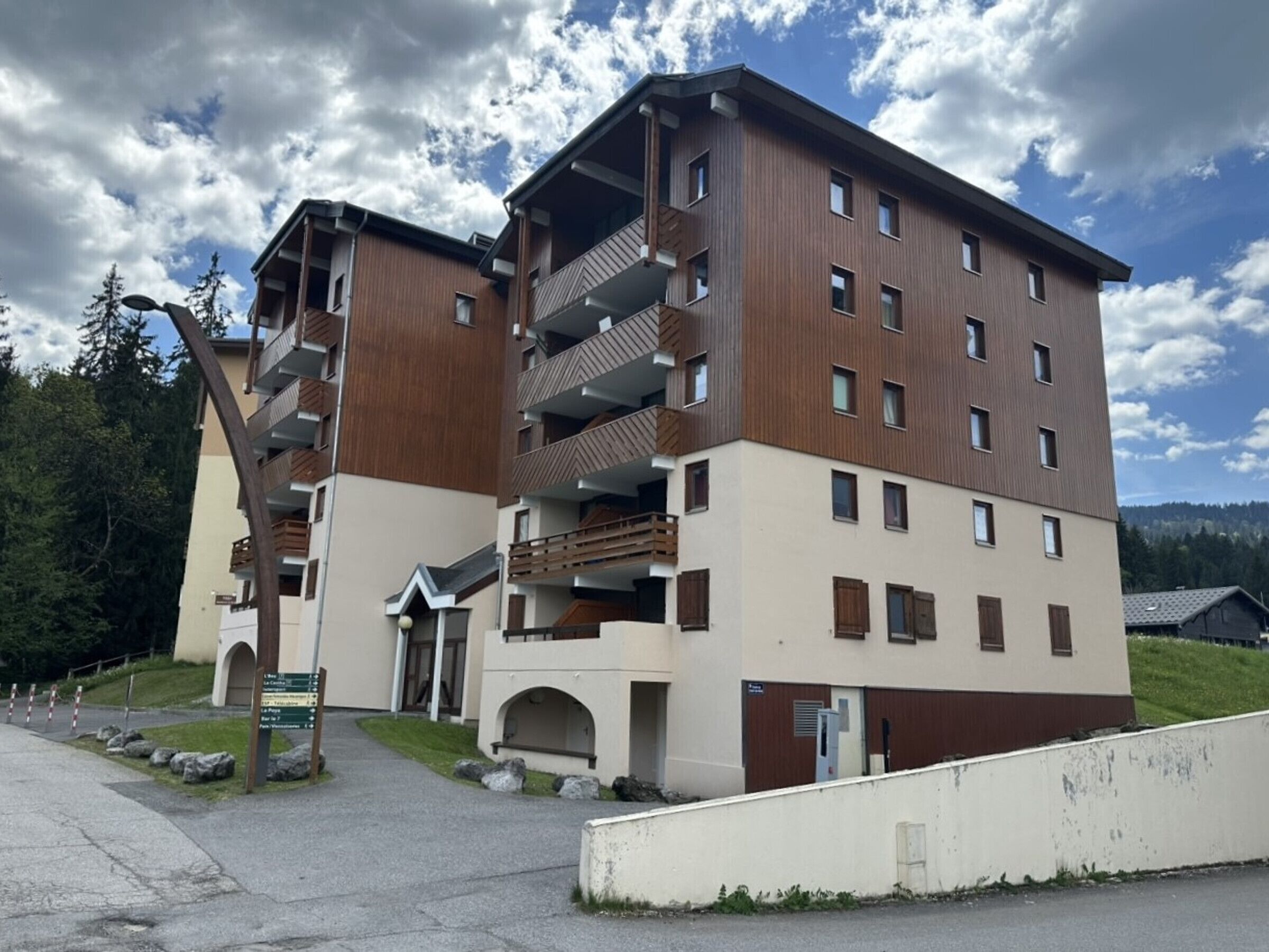 A multi-story hotel with balconies, a central entrance, and a parking area.