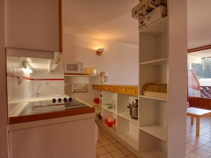 Una cocina compacta con microondas, estufa y un lavamanos pequeño.