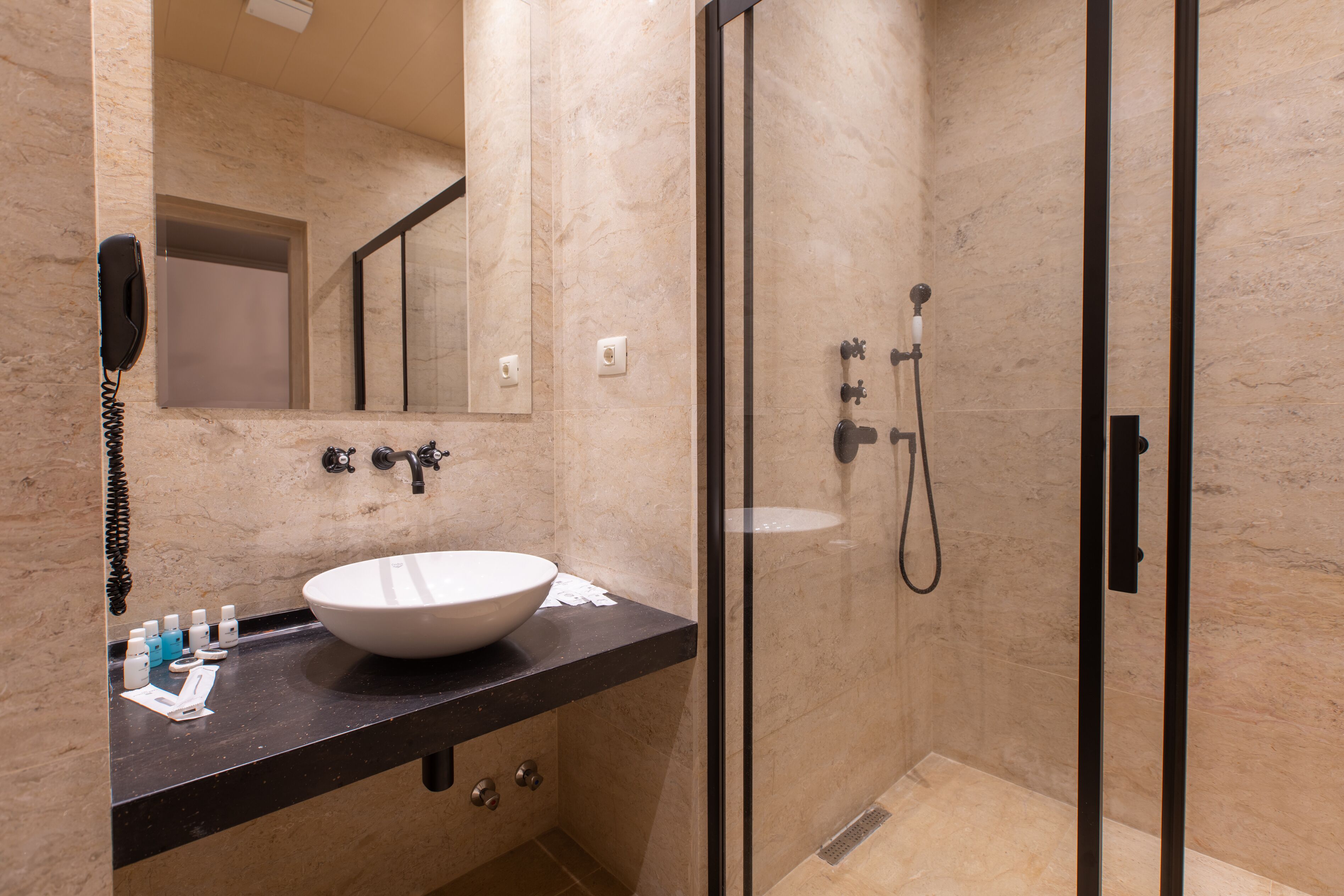 Ein modernes Badezimmer mit einem großen Waschbecken, einem Spiegel, einer Dusche und einem Telefon.