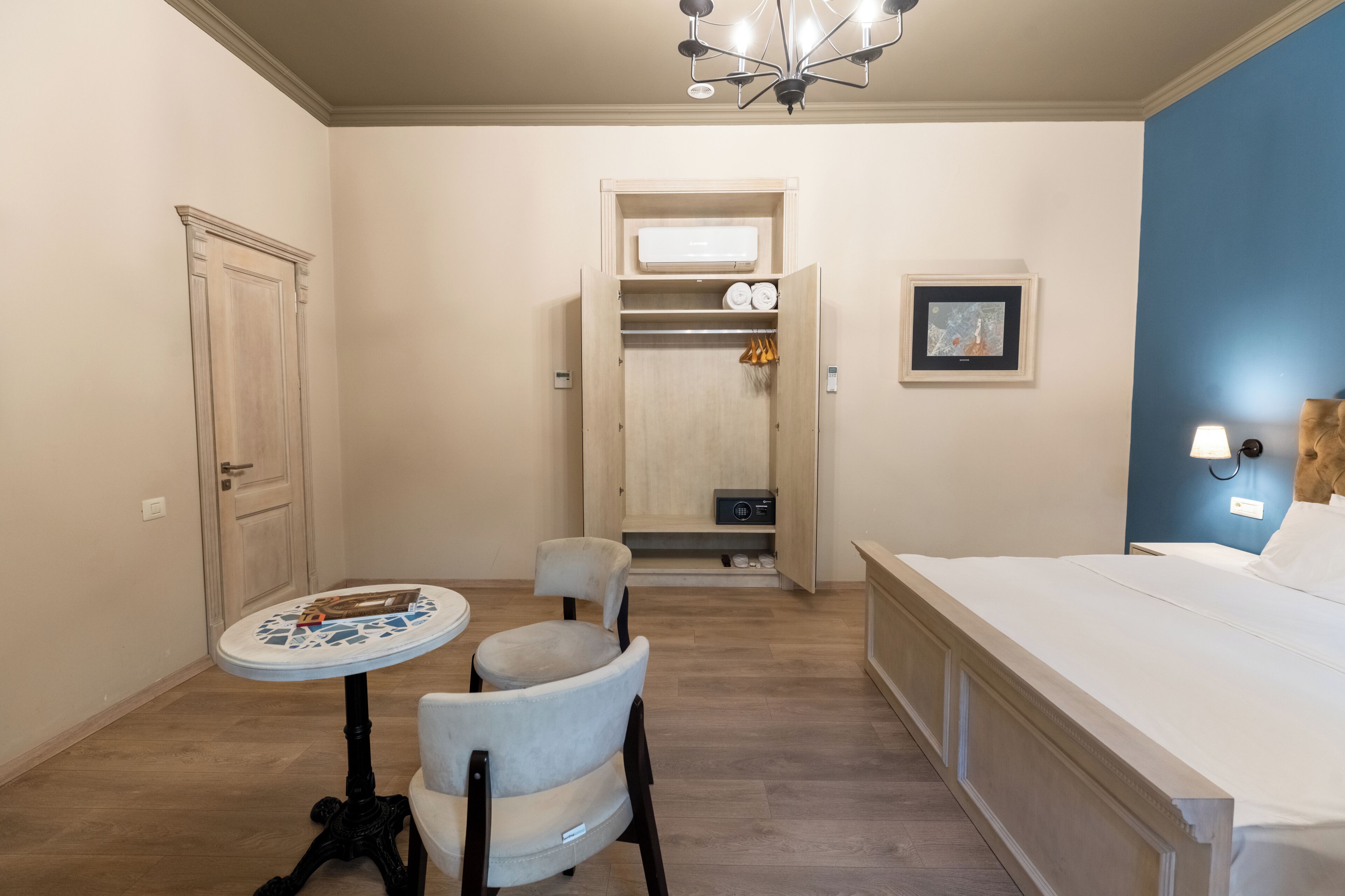 A bedroom with a bed, a desk with a chair, a wardrobe, and a small table.
