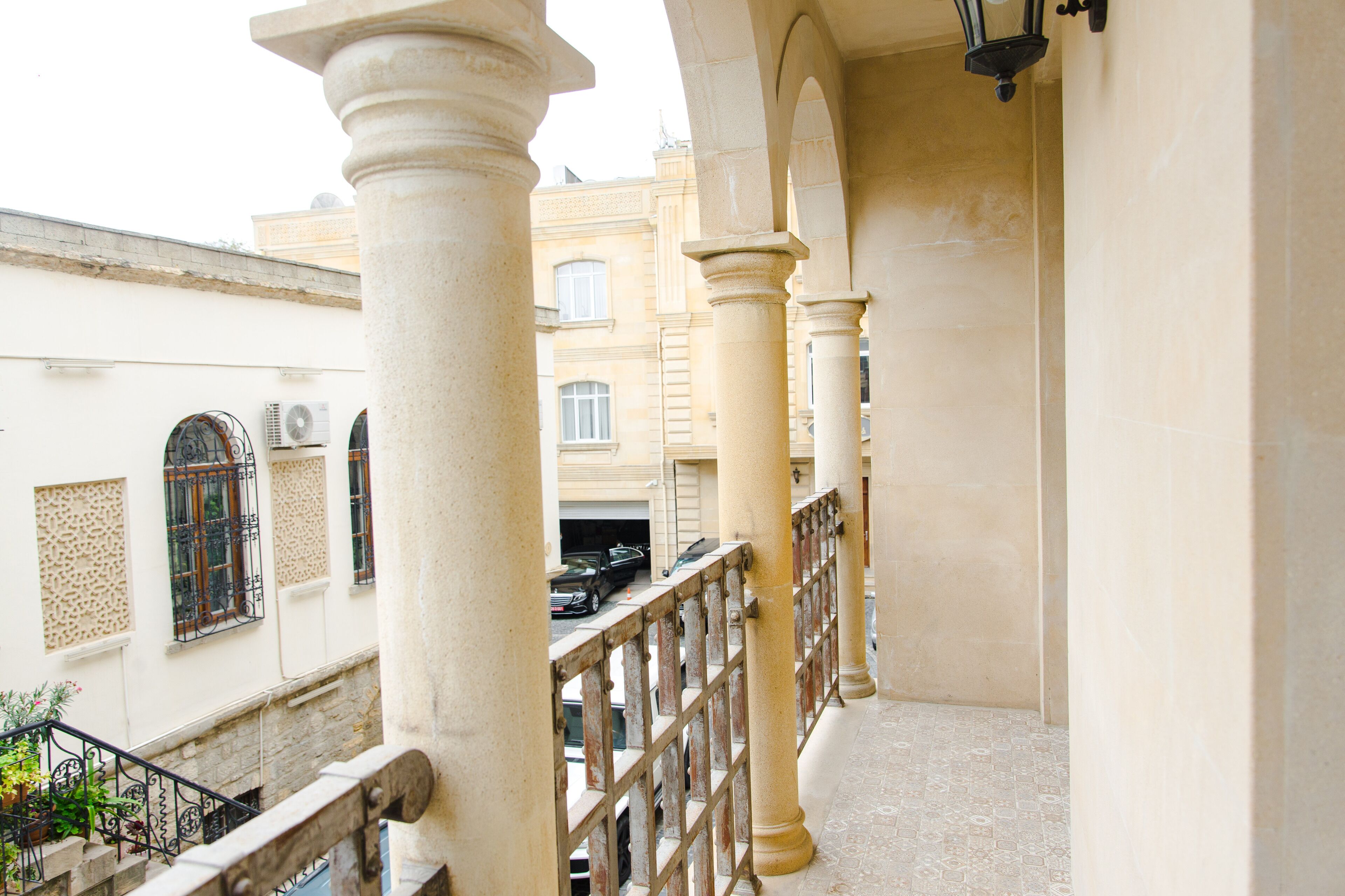 A balcony with columns, a railing, and a view of buildings in the background.