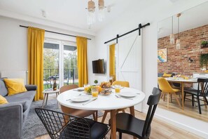 Un espace repas moderne avec une table ronde, des rideaux jaunes et un mur en briques.