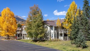 A multi-story building with balconies, surrounded by autumn-colored trees and a clear blue sky. - Nice Updated Condo. Hot Tub. Access to Lake. (Frisco)