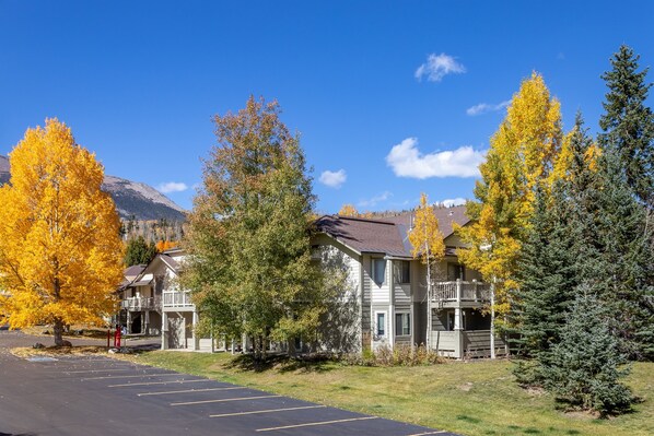 A multi-story building with balconies, surrounded by autumn-colored trees and a clear blue sky. - Nice Updated Condo. Hot Tub. Access to Lake. (Frisco)
