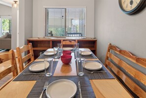 A dining area with a table set for four, chairs, a window with blinds, and a wall clock. - Nice Updated Condo. Hot Tub. Access to Lake. (Frisco)