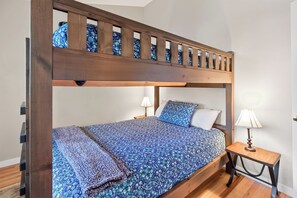 A bunk bed with a wooden frame, a patterned bedspread, two pillows, a bedside table with a lamp, and a wooden floor. - Nice Updated Condo. Hot Tub. Access to Lake. (Frisco)