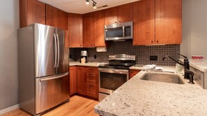 A modern kitchen with wooden cabinets, stainless steel appliances, a granite countertop, and a built-in oven. - Nice Updated Condo. Hot Tub. Access to Lake. (Frisco)
