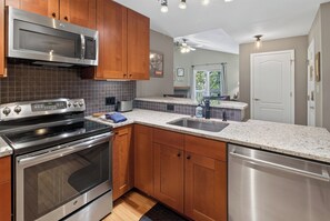 A modern kitchen with stainless steel appliances, wooden cabinets, and a granite countertop. - Nice Updated Condo. Hot Tub. Access to Lake. (Frisco)