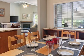 A dining area with a kitchen in the background, a fireplace, and a large window with blinds. - Nice Updated Condo. Hot Tub. Access to Lake. (Frisco)