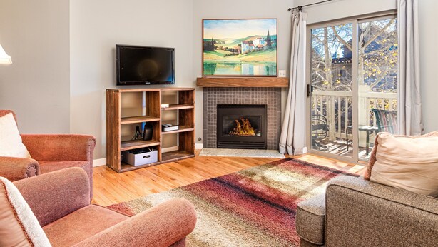 A living room with a fireplace, a television, and a view of the outdoors. - Nice Updated Condo. Hot Tub. Access to Lake. (Frisco)