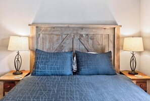 A bedroom with a wooden headboard, two bedside lamps, and a bed with a blue patterned bedspread. - Nice Updated Condo. Hot Tub. Access to Lake. (Frisco)