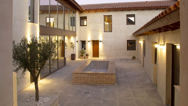 A courtyard with a tiled floor, a central seating area, and a tree.