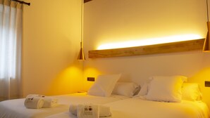 A hotel room with a large bed, two bedside tables, a wooden headboard, and a hanging light fixture.