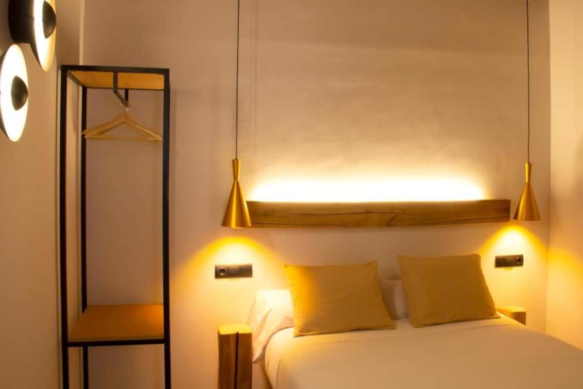 Un dormitorio con cama, lámparas de noche, armario ropero y estante en la pared.