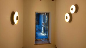 A narrow hallway with a sloped ceiling and a small window at the end.