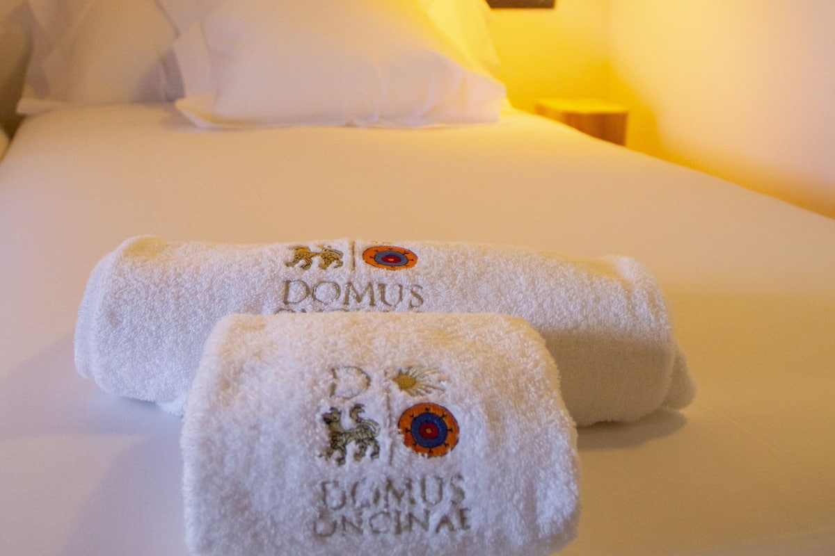 Une chambre d’hôtel avec un lit bien fait, une tête de lit en bois et une lampe suspendue.