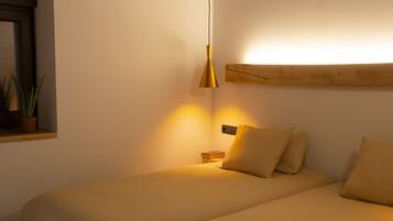 Un dormitorio con cama, mesita de noche, luz de pared y planta en maceta.