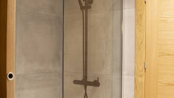 A glass-enclosed shower with a handheld showerhead and a rain shower head.
