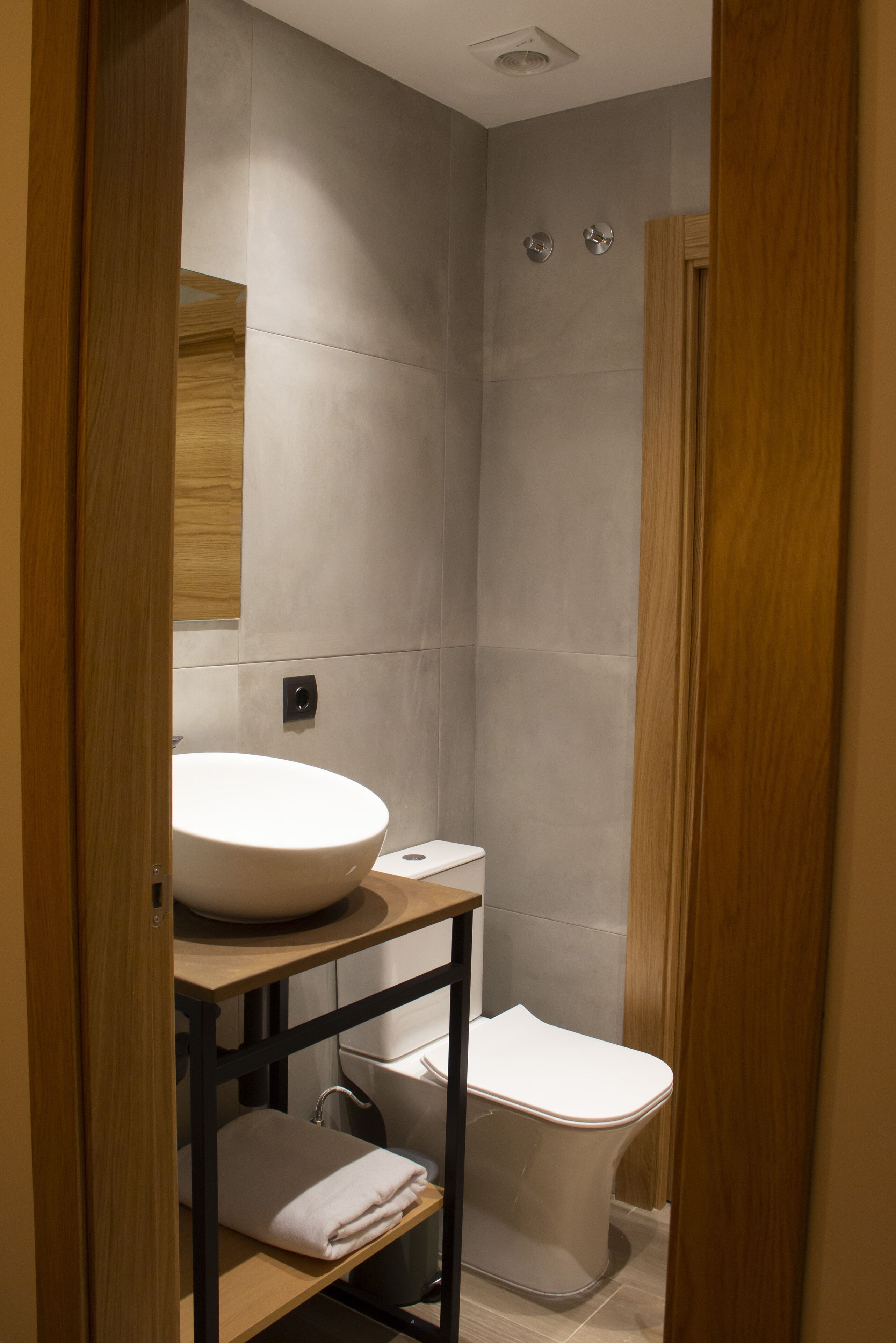 A modern bathroom with a large white sink, a toilet, and a shower area.