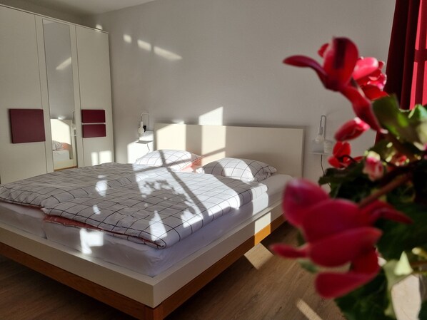 A modern bedroom with a bed, bedside tables, and a wardrobe.