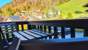 A wooden deck with a bench, overlooking a hillside with houses and solar panels. - Water lily Apartment (Berchtesgaden)