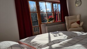 A bedroom with a bed, a chair, a window with curtains, and a radiator. - Water lily Apartment (Berchtesgaden)