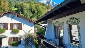 A traditional chalet with a balcony, surrounded by lush greenery and a mountain backdrop. - Water lily Apartment (Berchtesgaden)
