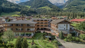 A hotel with multiple floors, a courtyard, and a mountain backdrop. - Alpenblick Hotel (Valle Aurina)