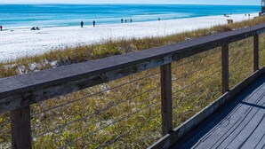 A wooden boardwalk leading to a beach with a restaurant named "Wailes Pier" in the background.