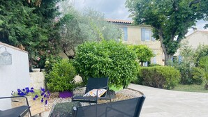 An outdoor patio with a table and chairs, surrounded by various plants and trees. - mas (Tarascon)