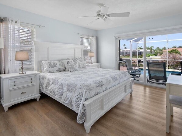A bedroom with a bed, nightstands, a desk, and a chair. - Waterfront 3BR/2BA Marco Island home with heated pool and Wi-Fi. (Marco Island)