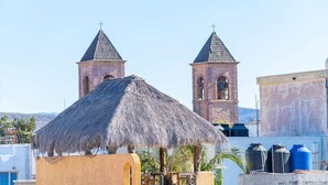 Un edificio con dos torres de campanas y una estructura con techo de paja al frente.