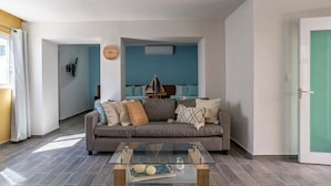 Un salon avec un canapé gris, une table basse en verre et un mur d’accent bleu.
