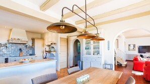 A spacious kitchen with a large island, modern pendant lighting, and a dining area with a wooden table and chairs.