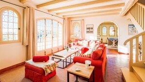 A spacious room with a red sofa, a wooden coffee table, and a staircase.